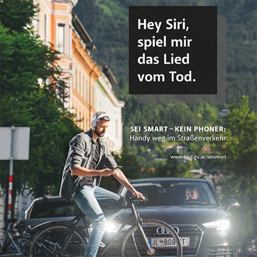 Plakat zeigt Fahrradfahrer auf Kreuzung, der auf sein Handy schaut, im Hintergrund rollt Pkw an 