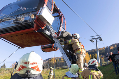 Feuerwehrleute führen Bergungsübung an der Patscherkofelbahn durch: Feuerwehrmann auf Leiter bei Gondel