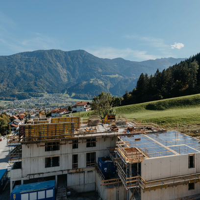 Baustelle mir Baukran und Bergen im Hintergrund.